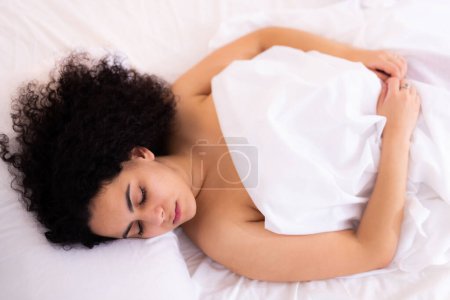 Young girl sleeping on white sheets in bed