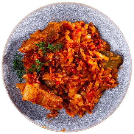 Fried pork ribs are complemented with portion of cabbage and pearl barley stew, decorated with sprigs of fresh dill hearty dish of national Belarusian cuisine. Isolated over white background