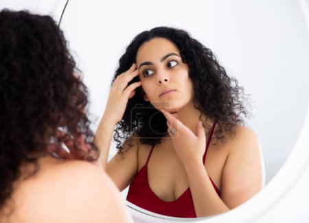Attraktive Frau überprüft ihr Gesicht morgens im Spiegel