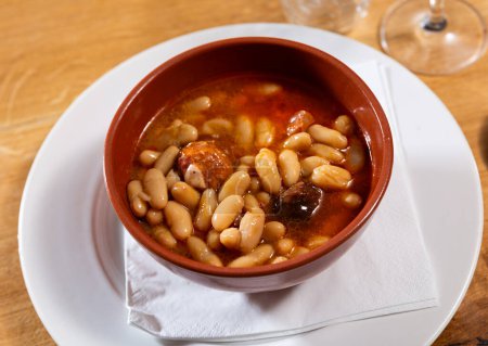 Asturian fabada soup with beans and pork served in bowl to table..