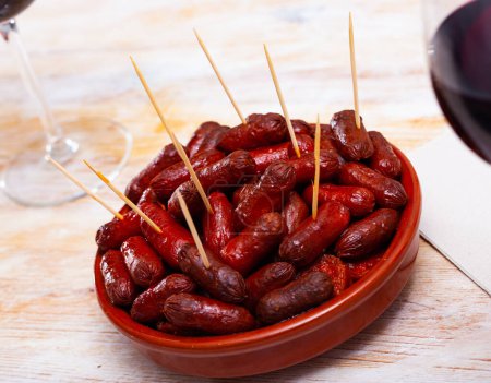 Hot mini chorizo sausages served in ceramic bowl. Popular Spanish appetizer for red wine