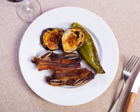Nicely served plate of tasty brazilian barbecued steak with eggplants and chili peppers
