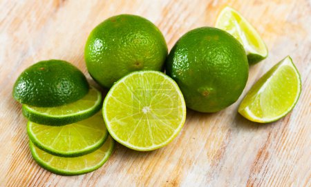 Picture of cut fresh raw green limes on wooden table in home kitchen