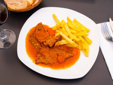 Hot dish is roast veal stew in thick red tomato sauce with vegetables. Meat is supplemented with French fries roasted potatoes. Halves of freshly baked white baguette harmoniously complement food