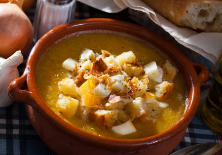 Healthy vegetable cream soup with croutons and cheese served in ceramic bowl