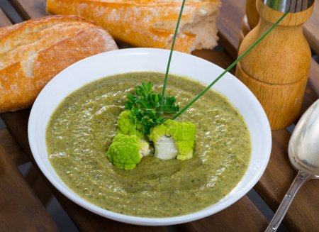 Bowl of delicious creamy broccoli soup garnished with greens
