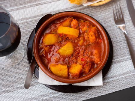 Plate of hearty and flavorful Patatas a la riojana, traditional Spanish dish of potatoes simmered with slices of chorizo sausage, pancetta, vegetables, spices and red wine
