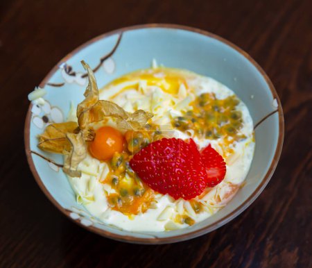 Delicate Brazilian passion fruit mousse with natural yogurt, sliced fresh strawberry and physalis. Exotic fruity dessert