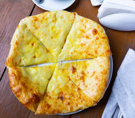 Delicious dish of Georgian cuisine is khachapuri Iveria with suluguni cheese and cut into pieces