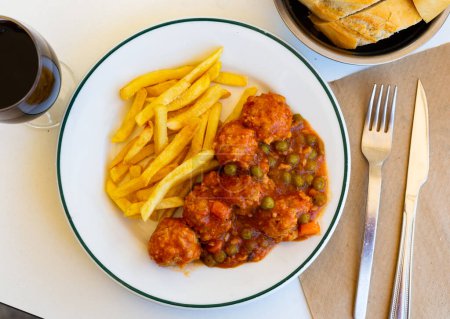 Middle-Eastern meat balls in tomato sauce with refreshing taste from the parsley and turmeric served with french fries