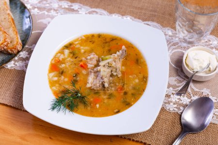 Popular dish of Russian cuisine is pickle soup with meat, cooked on basis of pickled cucumbers and pearl barley or rice, decorated with sprig of parsley on top