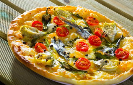Délicieuse pizza aux anchois, artichauts, fromage et tomates séchées au soleil..