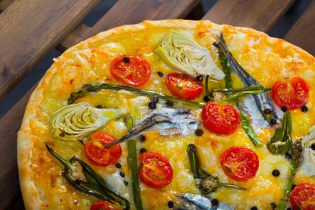 Tasty Italian pizza with anchovies, sun-dried tomatoes, artichokes, jalapeno and cheese..