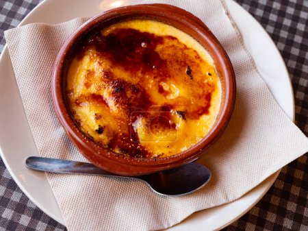 Popular Spanish custard dessert Catalan cream from milk and eggs with crispy sugar crust served in earthenware bowl..