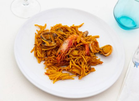 Plato tradicional de mariscos español fideua con salsa aioli en un restaurante