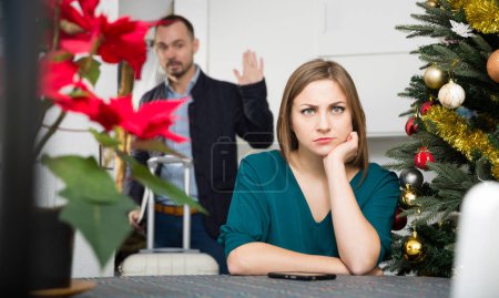 Unhappy couple quarreling because of business trip of husband on Christmas holidays