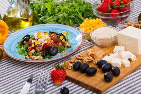 Salat mit Rucola, Oliven, Feta-Käse, Mais und Walnüssen und seinen Zutaten in der Küche.