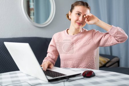 Mujer joven que experimenta dolor de ojos después de trabajar en el ordenador portátil en casa
