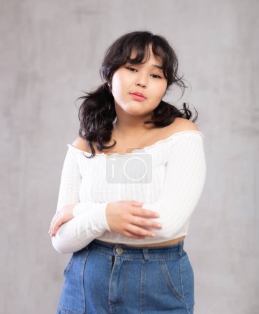 Portrait of pensive young asian girl in casual clothes posing in studio..