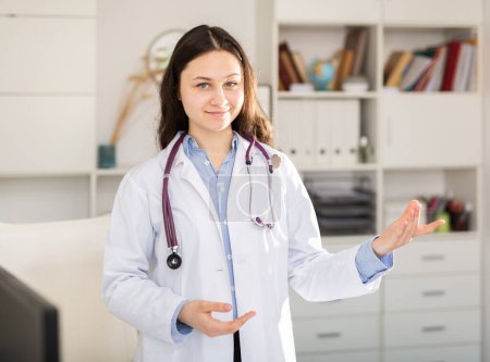 Doctora joven positiva en prácticas que se somete a una pasantía en los puestos de la clínica en una oficina de residentes bien iluminados