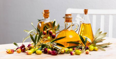 Flaschenweise Olivenöl und Zweige mit Blättern und Oliven. Hochwertiges Foto