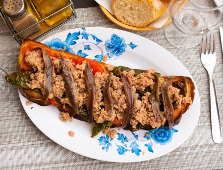 Traditional Spanish snack of toasted bread with chopped tuna, anchovy filets and baked green and red pepper slices