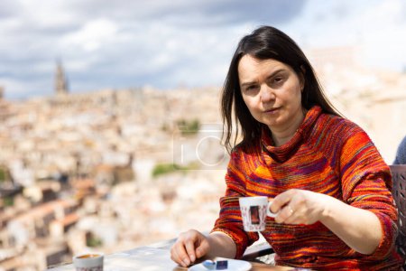 Porträt einer Touristin beim Kaffeetrinken an einem Tisch mit Blick auf Toledo, Mirador del Valle, Spanien