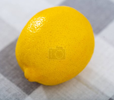 There is whole yellow lemon on wooden table. Lemon peel texture close-up, isolated