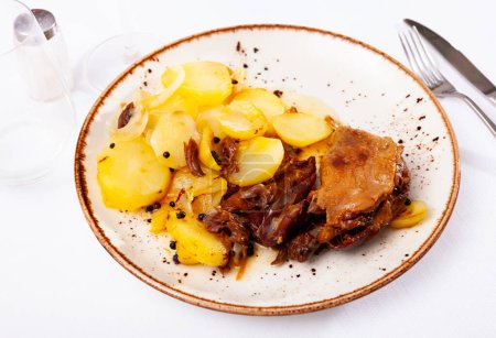 French cuisine, fried duck confit with roasted potatoes on a plate in a restaurant