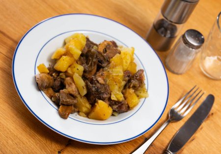 Auf dem Tisch steht ein deftiges Mittagessen - Kalbfleisch mit geschmortem Gemüse. Champignons, Kartoffeln, Erbsen mit großen Rinderfiletstücken gekocht.
