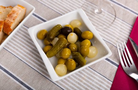 Marinated whole green olives, gherkins and pearl onions served as snack. Traditional Spanish appetizer