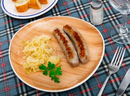 Appetizing sausages served with sauerkraut, bread and parsley