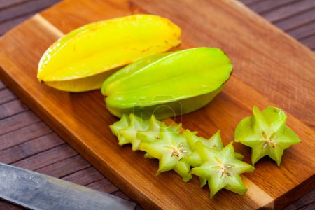 Whole and sliced fruits fresh carambola on wooden table. Healthy vegetarian ingredient