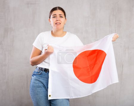Fille frustrée avec drapeau du Japon drapeau dans ses mains. Isolé sur fond gris