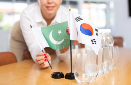 Vorbereitung auf internationale Verhandlungen. Bürokoordinator, der die Nationalflaggen Südkoreas und der Islamischen Republik Pakistan auf den Tisch legt, abgeschossen. Konzept der bilateralen diplomatischen Beziehungen