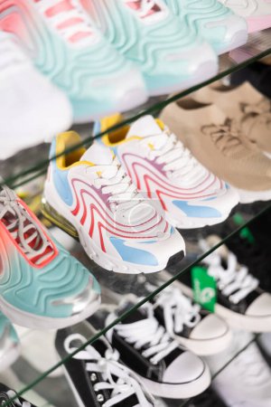 Pairs of sports sneakers arranged on glass showcase in shoe store