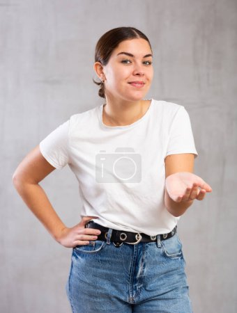 Photo of flirty young woman standing posing intriguingly against gray shadeless background