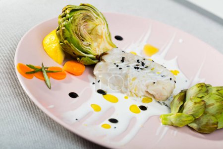 Hake Provencal recipe: fish fillets 250gr put out in frying pan with cream, garlic, olive oil, salt, pepper for 20 minutes. Clean artichoke and boil with lemon and salt. Season with balsamic