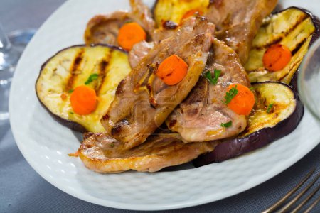Juicy slices of mutton with grilled eggplant and carrot on plate