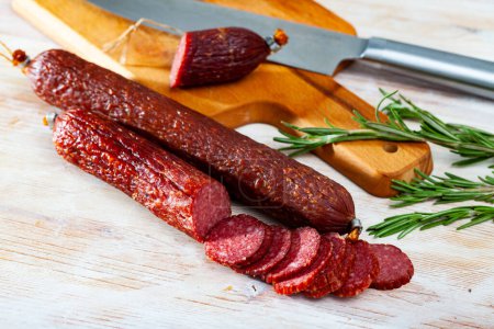 Image of russian smoked sausage cut in slices on a wooden surface, close-up ..