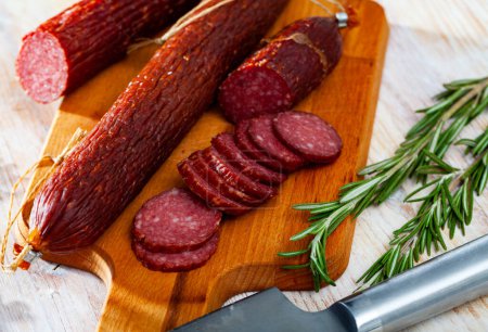 Fresh smoked russian sausage cut in slices on a wooden surface, close-up