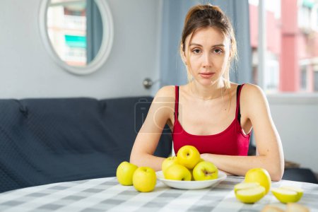 Portrait of a happy woman with apples at the table in the room at home. Diet and weight loss concept