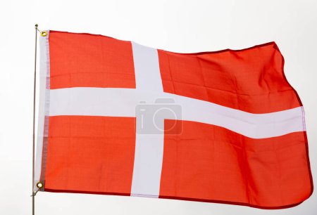 Large flag of Denmark on flagpole waving against sky and clouds