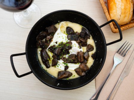 Typical Spainish dish of fried eggs served on top of bed of mashed potatoes parmentier with sauteed mushrooms