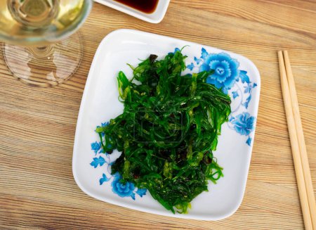 Japanischer Algensalat aufgetischt in einem Teller mit Sojasauce auf dem gedeckten Restauranttisch