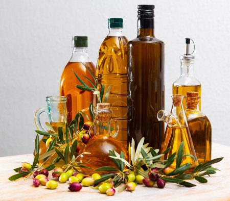 Flaschenweise Olivenöl und Zweige mit Blättern und Oliven. Hochwertiges Foto