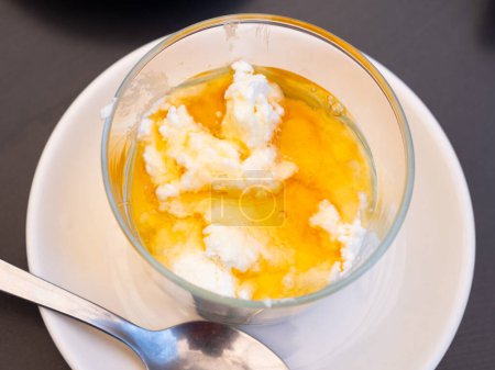 Queso mate de leche fresca con miel dulce dorada en vaso listo para comer. Alimento nutritivo saludable. Postre tradicional catalán ..