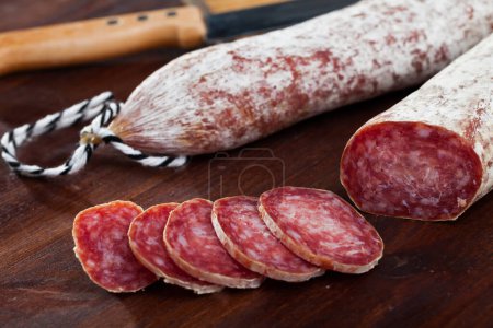 Spanish longaniza salami sausages cut in slices on a woodefn desk, close-up