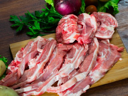 Raw lamb and vegetables assortment on natural wooden desk, cooking ingredients