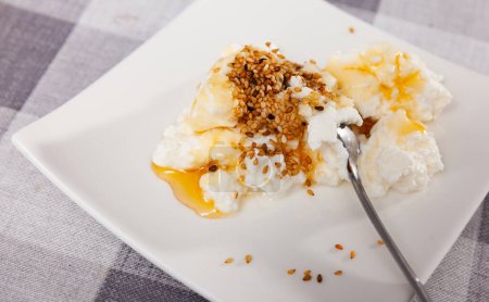 Köstlicher hausgemachter Frischkäse aus Ziegenmilch mit Honig und Sesam auf dem Teller. Beliebtes Milchprodukt. Katalanische Mato con